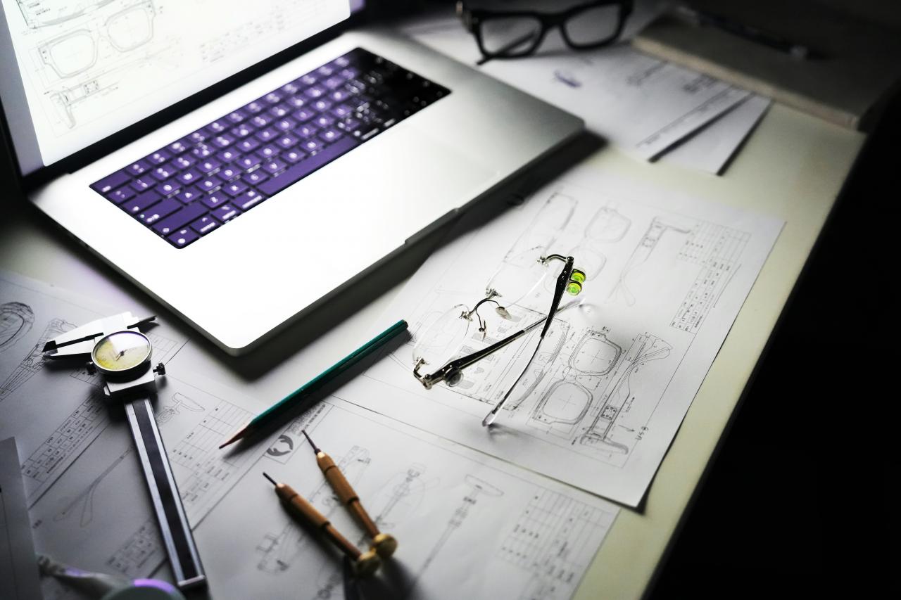 Meja dengan laptop, cetak biru, dan alat